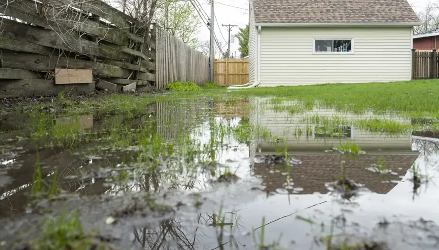 Storm water ponding across a backyard after heavy rain in St. Charles County