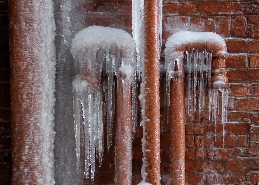 Ice-covered supply pipes along a brick wall during a St. Charles County cold snap